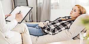 girl lying on couch while psychologist takes notes