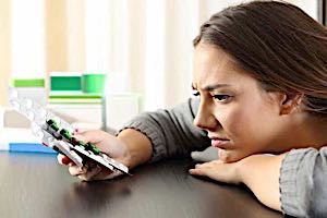 Doubtful unsure puzzled woman holding pills