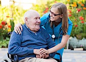 smilimg old man in wheelchair with friendly nurse