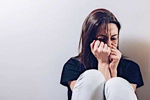 girl crying with clenched fists held to her injured face