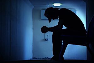 depressed man seated dark room