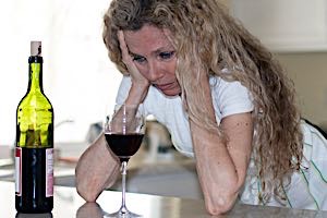depressed sad alcoholic woman with wine glass and bottle