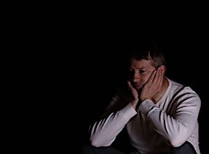 depressed man sitting alone with head in hands