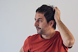 man scratching his head trying to solve a problem
