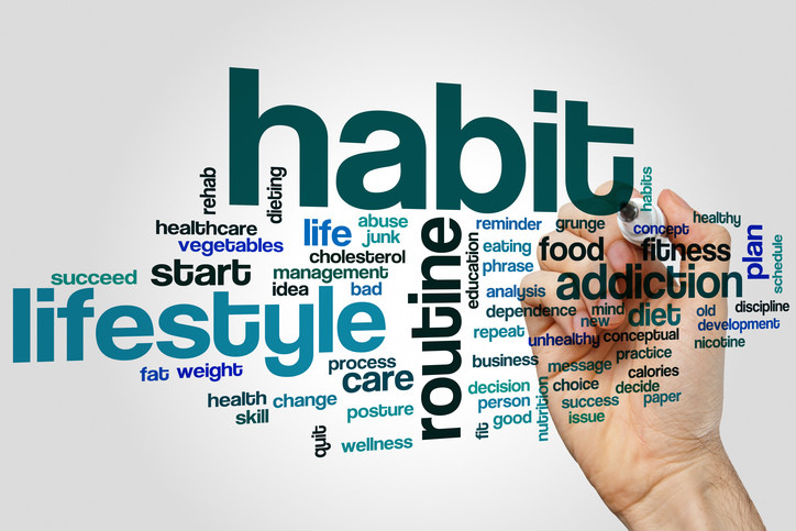 person writing the word 'habit' on a board