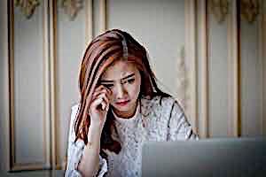 crying young woman looking at computer screen