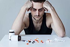 Man looking at pills spread on table