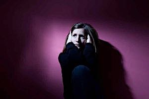 sad lonely woman crouched in a dark corner