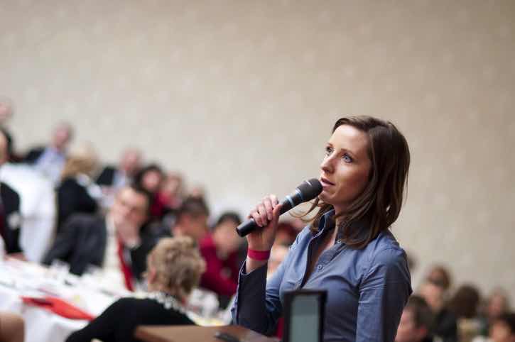 woman finding courage to speak into microphone at meeting