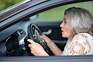 older woman scared behind steering wheel.