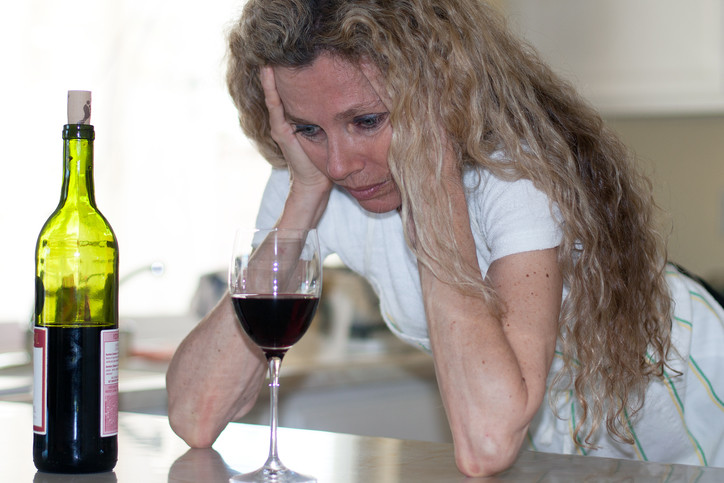 depressed woman with wine and head in hands