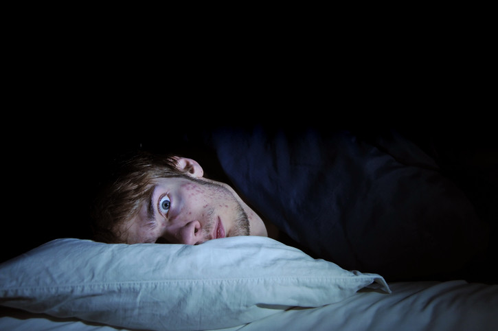 restless man awake in bed with eyes wide open