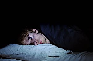 restless man awake in bed with eyes wide open