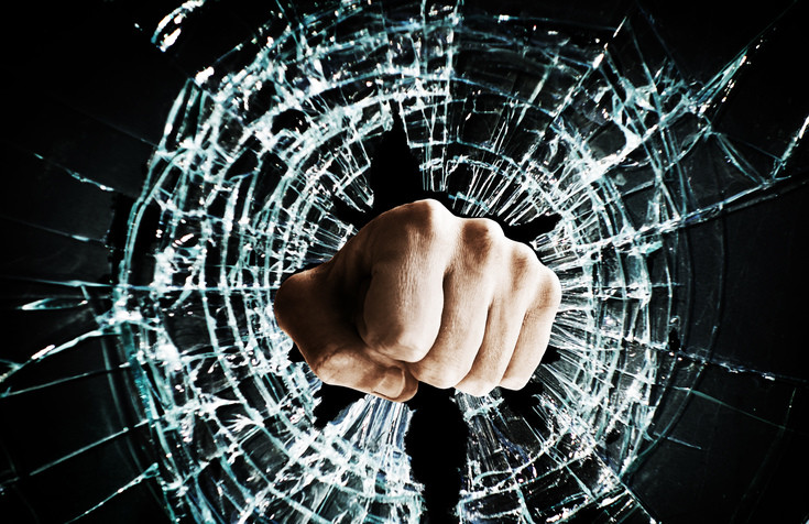 man punches fist through glass window