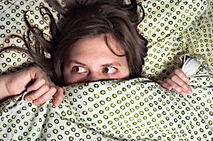 Scared woman hiding under the sheets