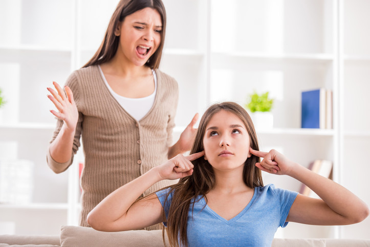 Woman puts fingers in her ears to block shouting from mother