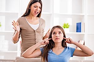 Woman puts fingers in her ears to block shouting from mother
