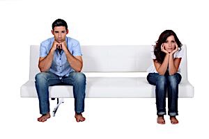 man and woman sitting apart from each other and sulking with chins in hands