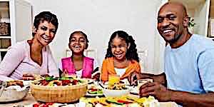 happy family seated at table eating healthy dinner