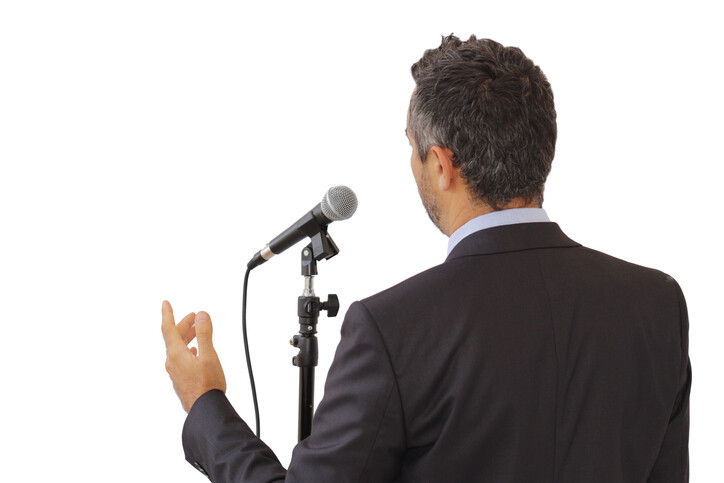 man public speaking at microphone