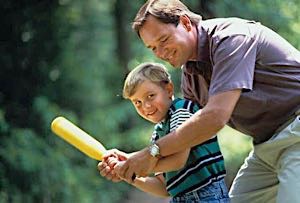 happy father teaching happy son how to hold a baseball bat