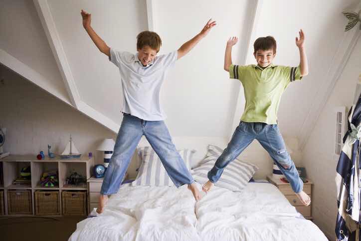 two happy boys jumping on a bed