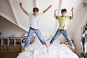 two happy boys jumping on a bed