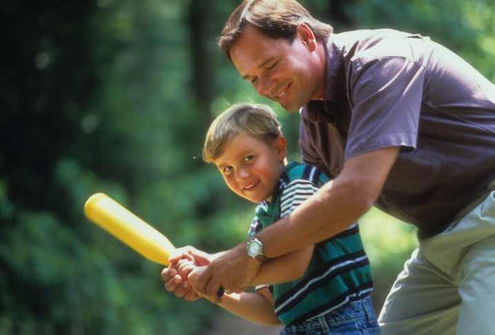 Father helping son hold baseball bat