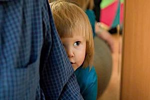 shy little girl hiding behing mother's skirt