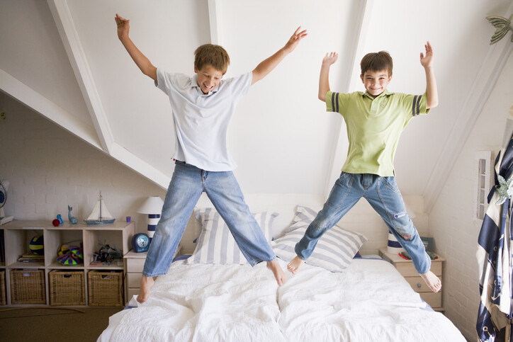 two boys kids jumping bouncing on bed