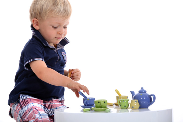 Boy toddler is playing with teacup serving set