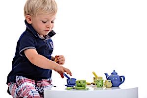 Boy toddler is playing with teacup serving set
