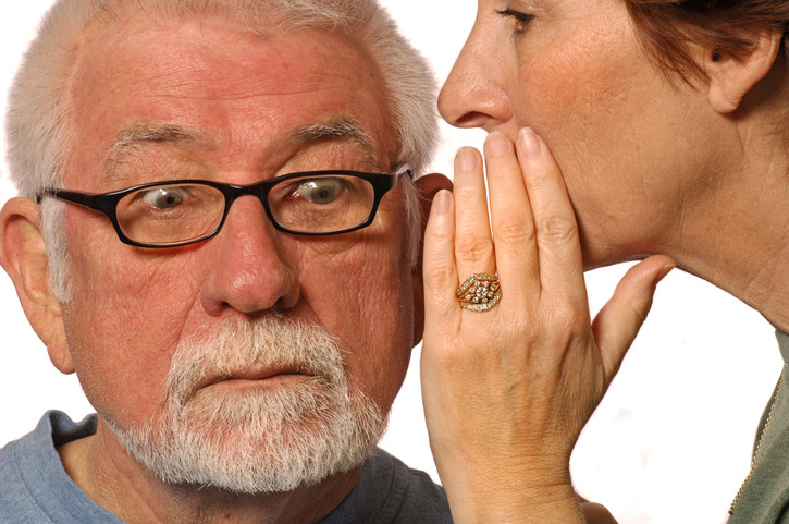 woman whispering lies into astonished man's ear