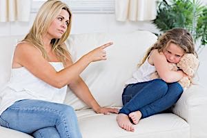 angry mother pointing finger at cowering child