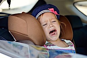 young child having temper tantrum in car seat
