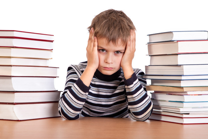 angry kid next to pile of school books
