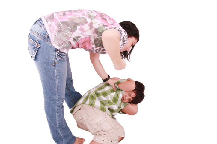 Woman physically punishing a young boy