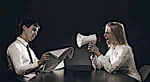 man reading paper ingoring woman yelling at him with bullhorn