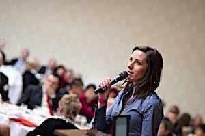 woman with microphone speaking to large group