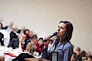 woman with microphone speaking to large group