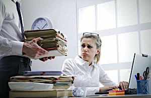Woman looks resentfully at man bringing her more paperwork