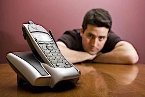 man waits anxiously by a cell phone