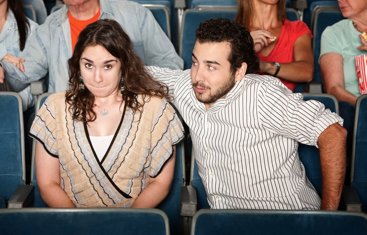 Aggressive man sneaking closer to his date while watching a movie