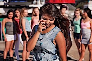 Insecure girl with low self esteem standing with back turned away from classmates