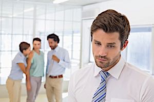 coworkers whispering behind sad man's back