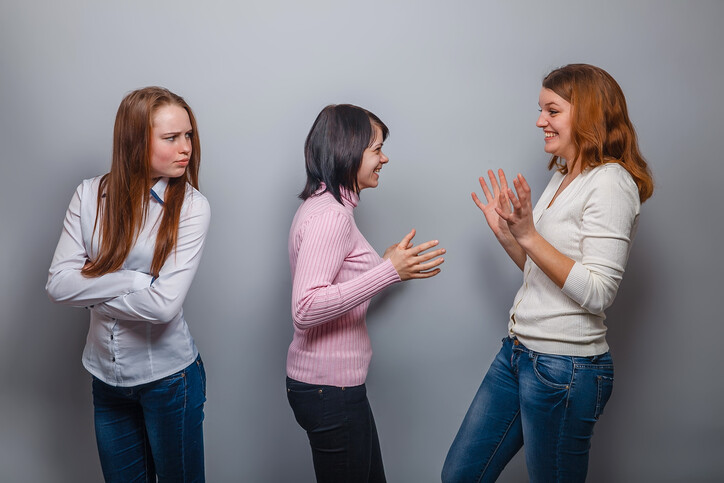 angry woman scowling at two happy friends 