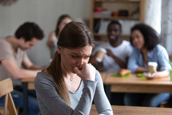 woman sitting alone avoiding others nearby