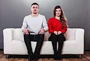 Shy man and woman sitting together on a couch