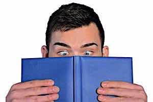 man reading with wide eyes glued to open book
