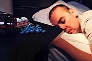 man sleeping with pile of pills next to him